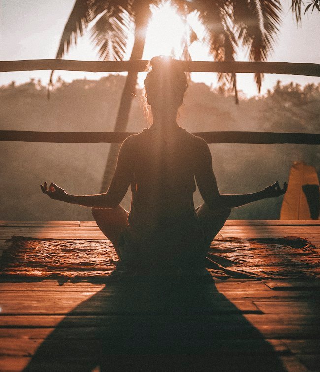 Woman meditating at sunrise